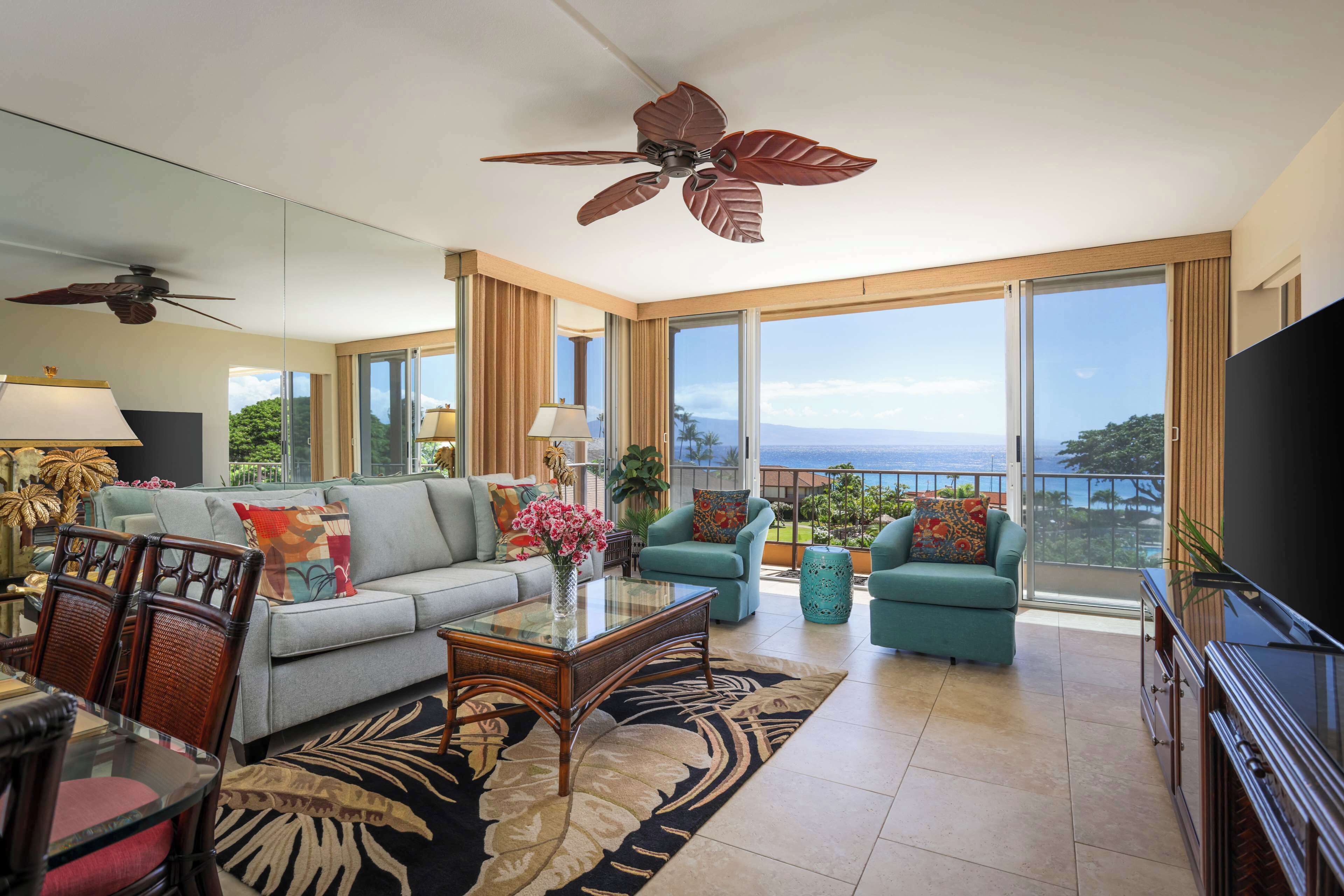 A spacious living room with a sofa, armchairs, a coffee table, and a TV.