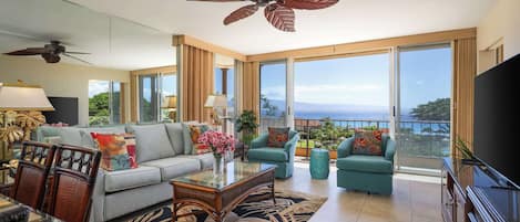 A spacious living room with a sofa, armchairs, a coffee table, and a TV.