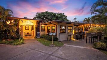A restaurant with outdoor seating, a signboard, and a well-lit entrance.