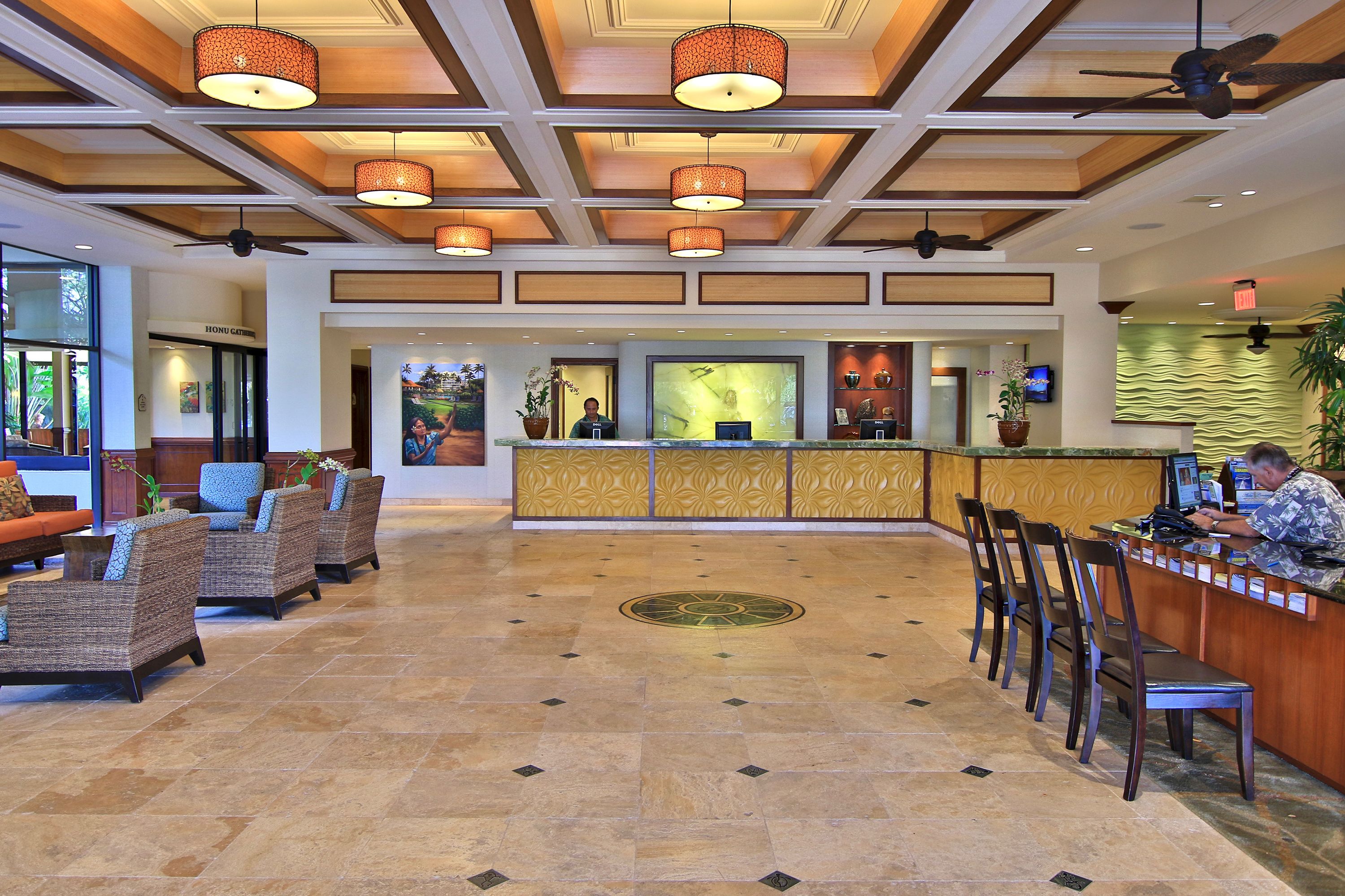 A hotel lobby with a reception desk, seating area, and a large screen.