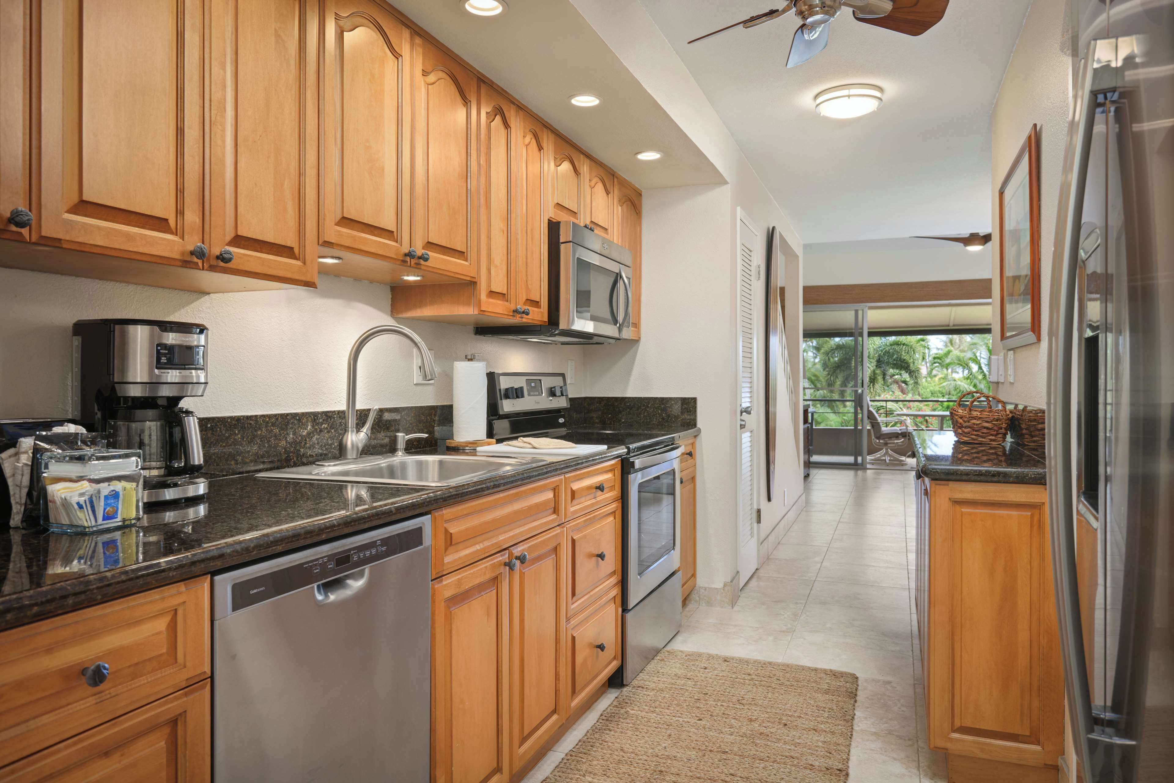 A kitchen with wooden cabinets, stainless steel appliances, a dishwasher, and a large window.