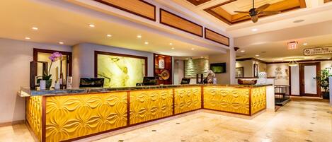 A reception area with a marble counter, ceiling fans, and a sign for the spa.