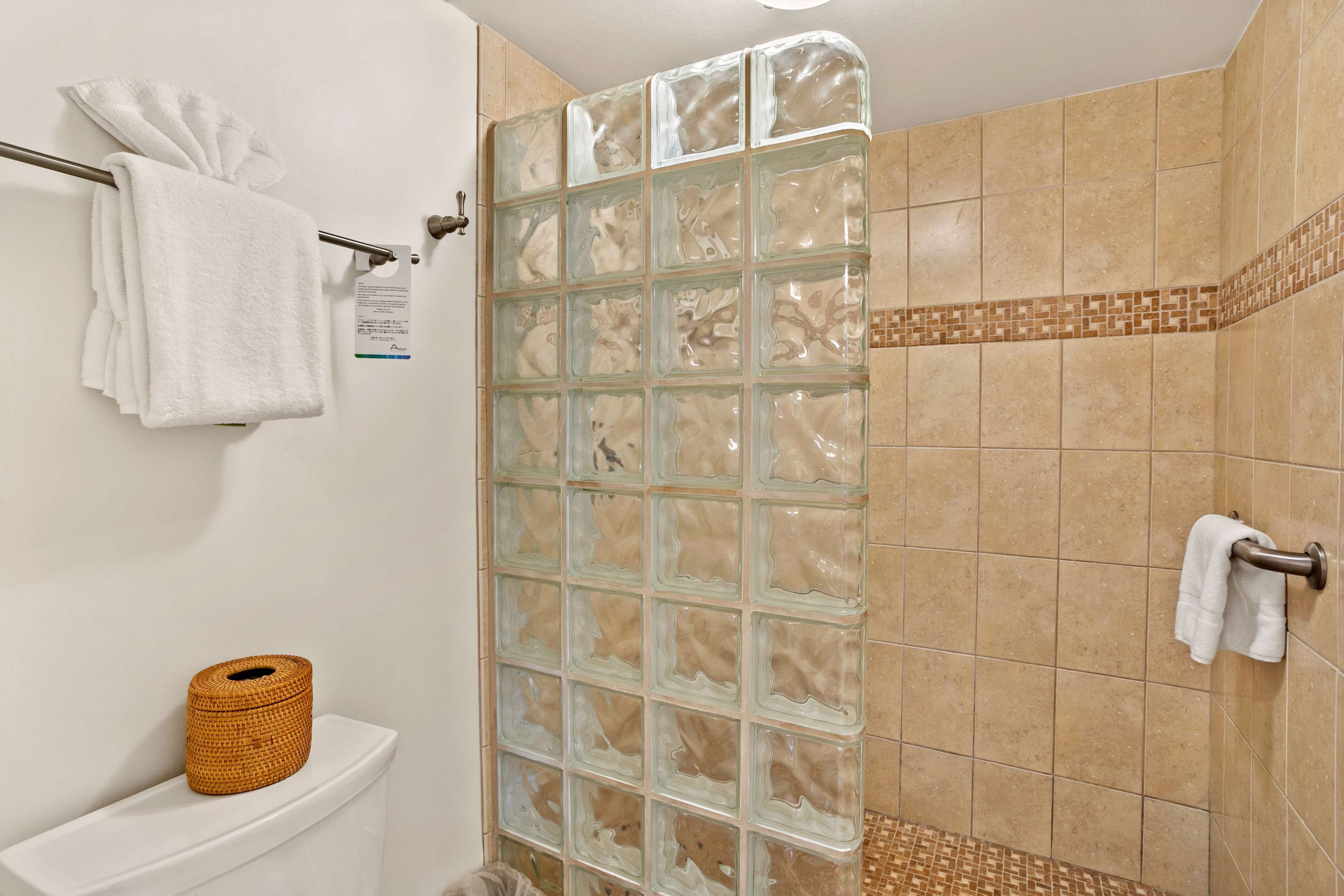 Un baño con cabina de ducha de vidrio, un inodoro con soporte para papel higiénico y un perchero para toallas.