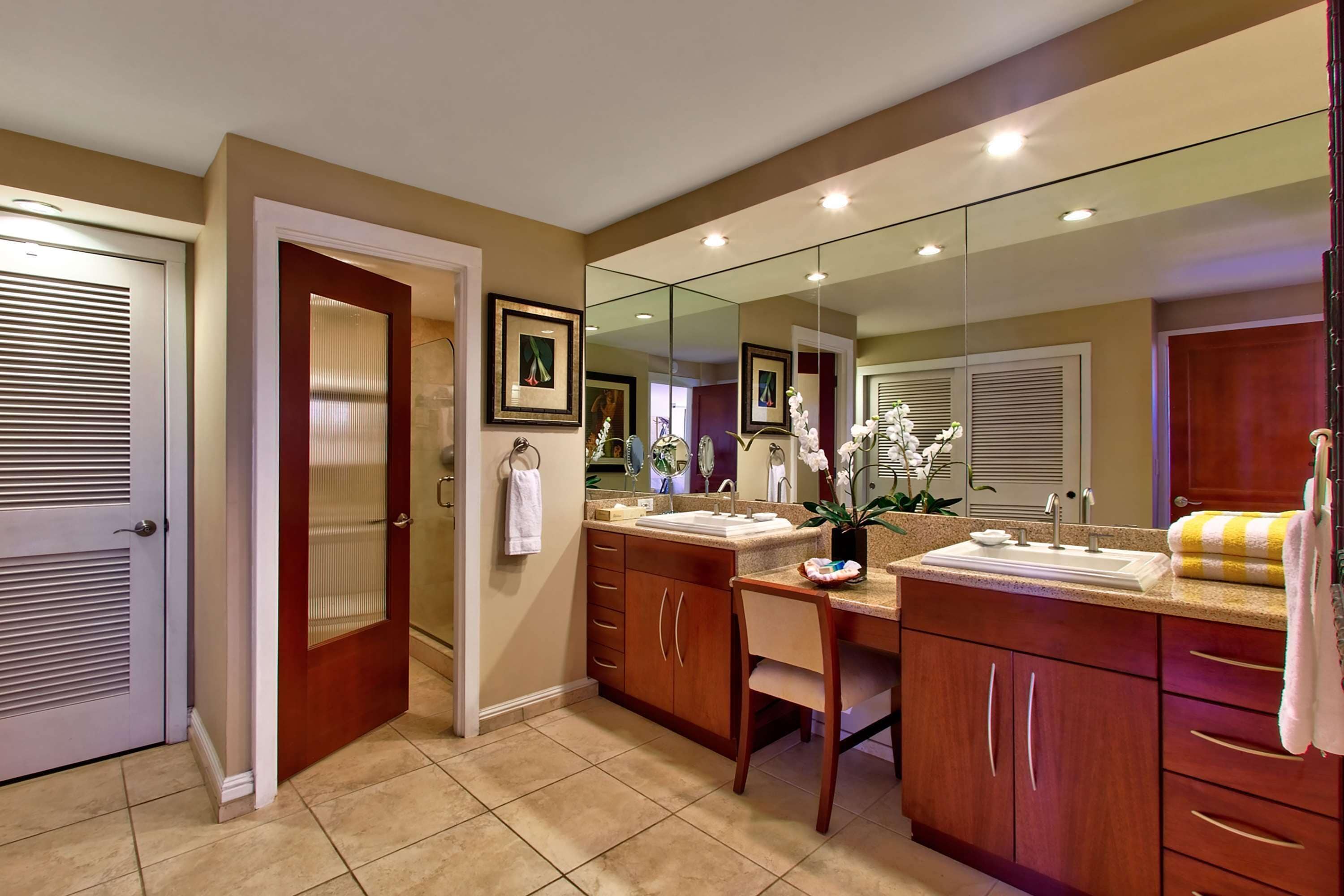 A bathroom with a double sink, a mirror, and a toilet.