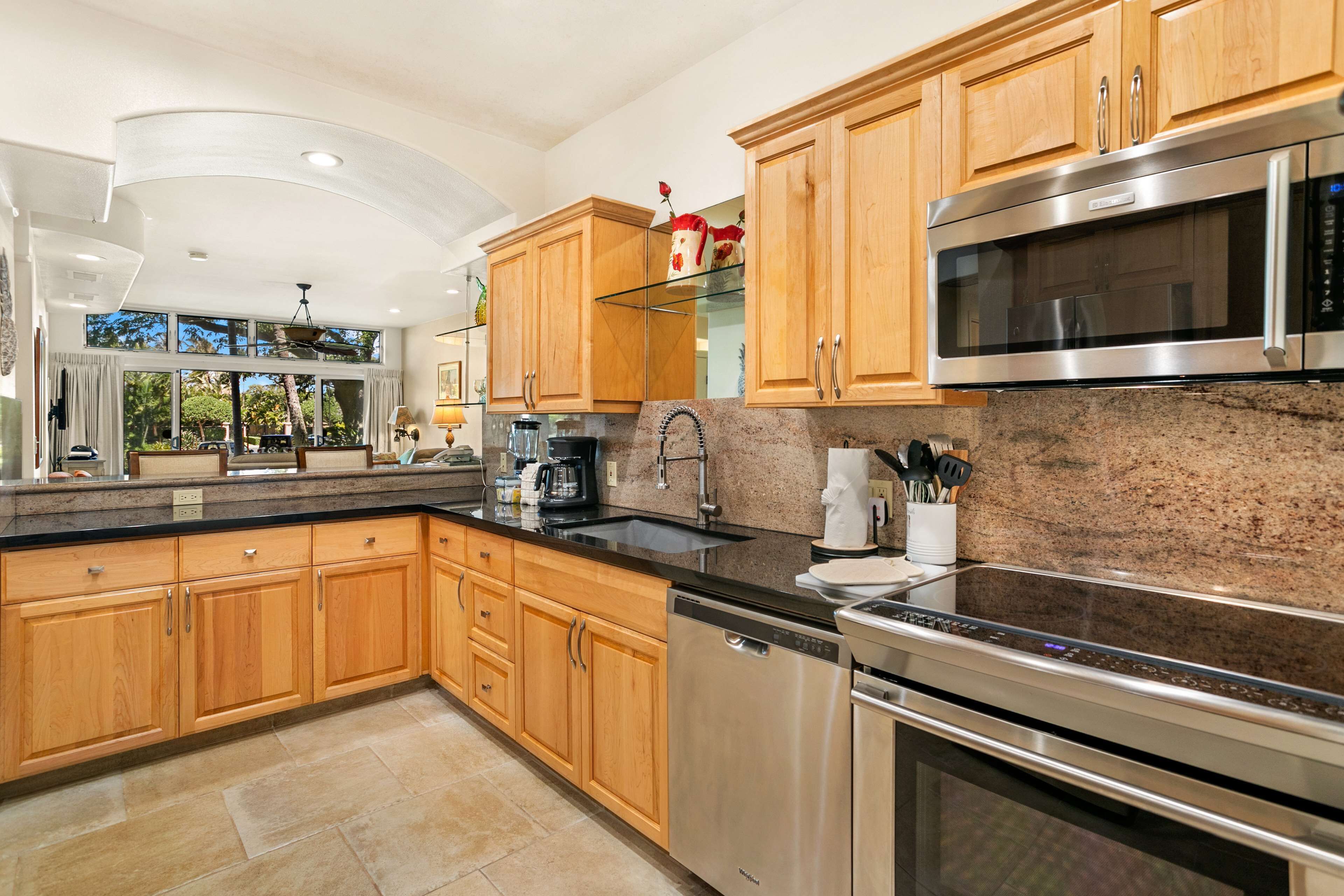 A modern kitchen with wooden cabinets, stainless steel appliances, and a granite countertop.