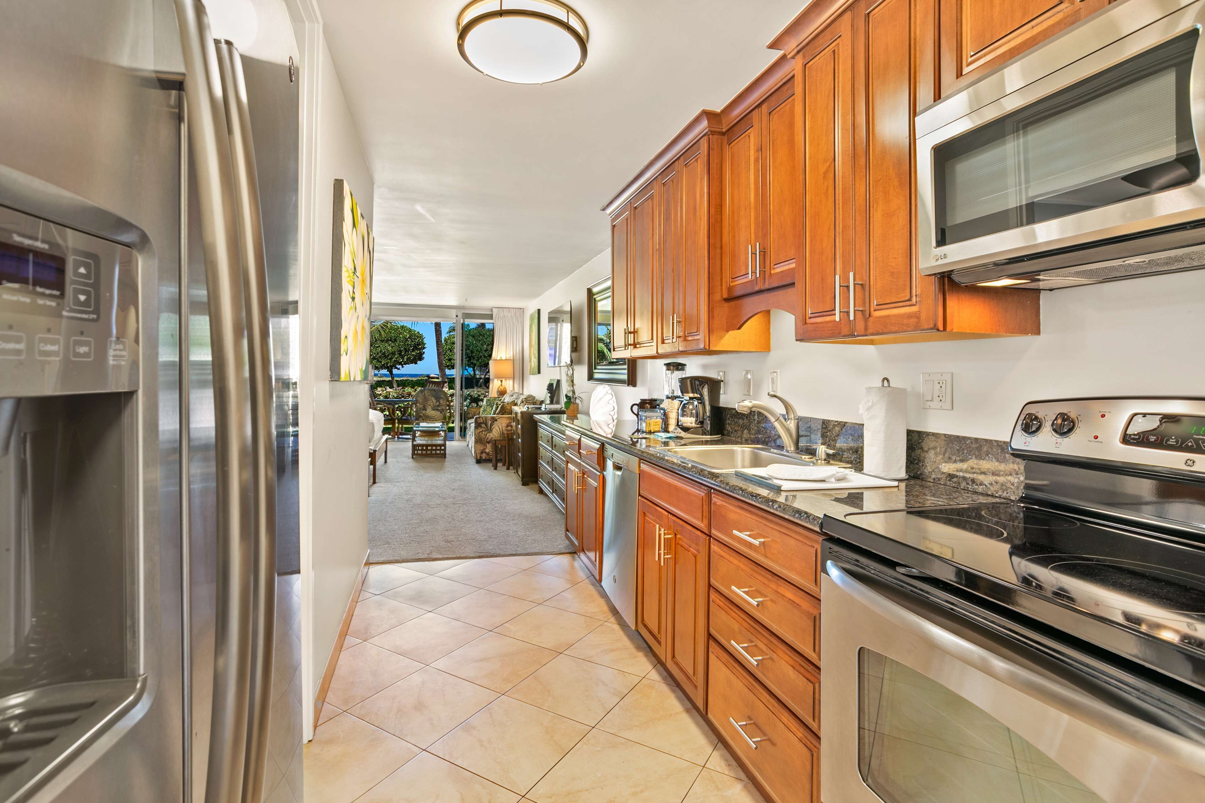 A modern kitchen with stainless steel appliances, wooden cabinets, and a view to the dining area.