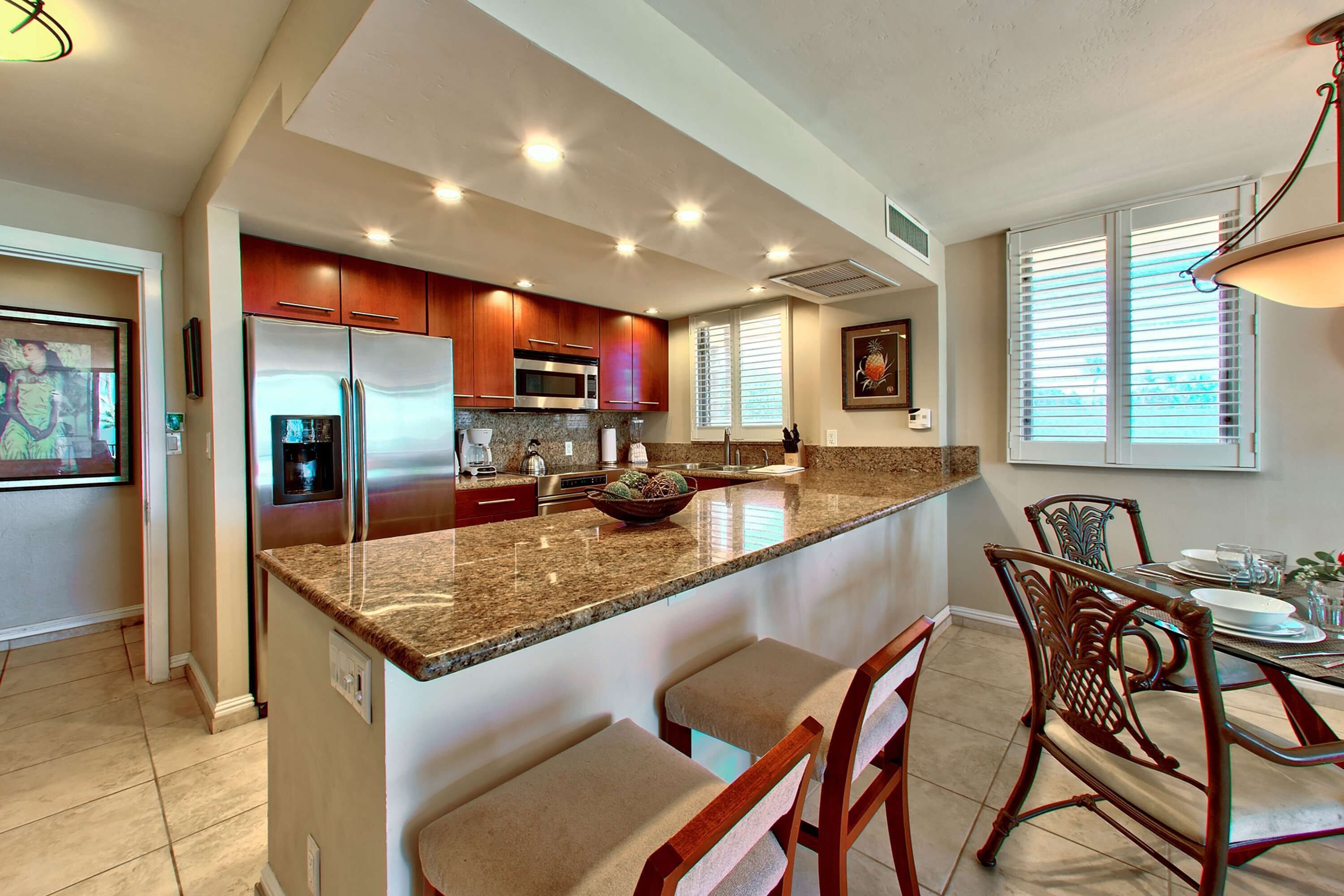 A kitchen with a large island, stainless steel appliances, and a dining area with chairs and a table.