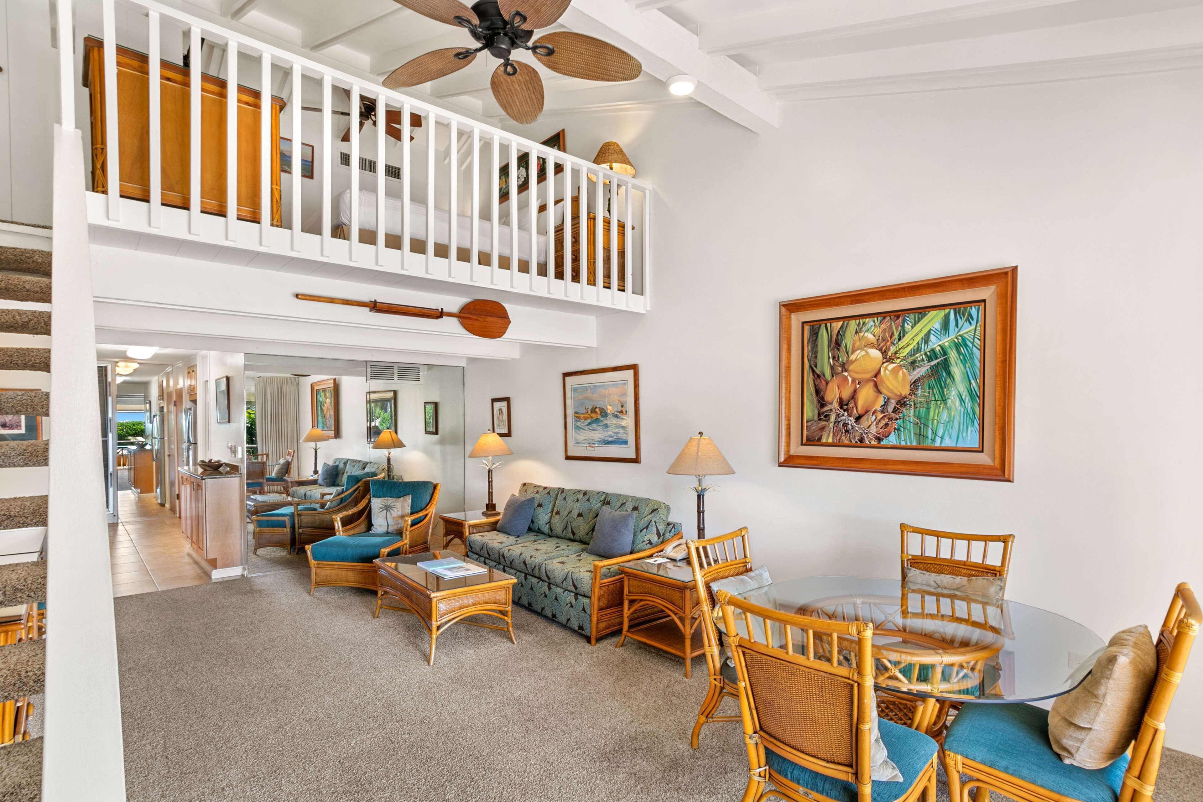 A spacious living area with a high ceiling, a balcony with a railing, and a dining area with wicker furniture.