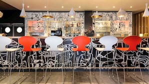 Angolo bar dal design moderno, con un bancone assortito di bottiglie e bicchieri, e una parete decorata con arte astratta.