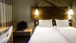 Une chambre d’hôtel avec un lit, des tables de chevet, un bureau et une chaise.