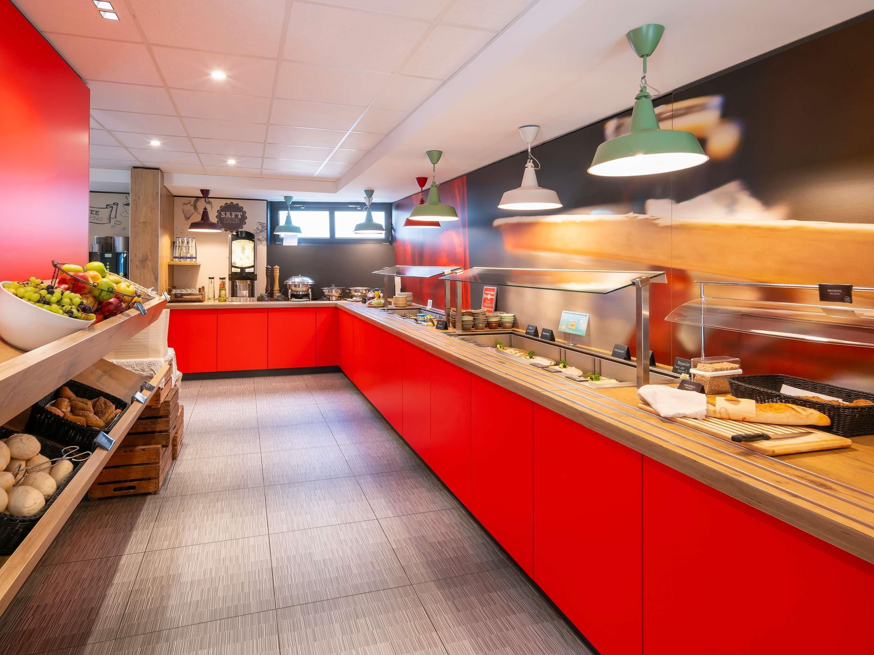 Um buffet de café da manhã com variedade de alimentos, esquema de cores vermelho e branco e luminárias modernas.