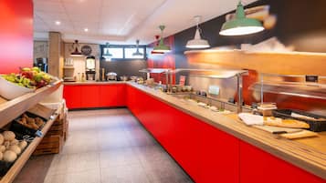 Um buffet de café da manhã com variedade de alimentos, esquema de cores vermelho e branco e luminárias modernas.