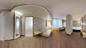 Une chambre d’hôtel avec un plafond incurvé, un lit, un bureau, un canapé et une petite table.