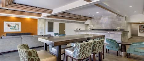 A modern kitchen with a bar area, seating, and a stone backsplash.