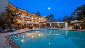 A hotel with a swimming pool, outdoor seating, and a covered area.