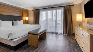 A hotel room with a large bed, a bench, a TV, and a dresser.