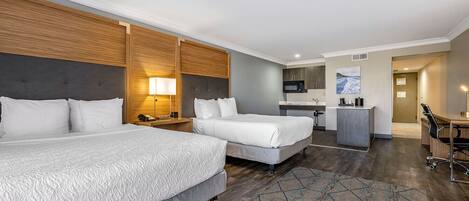Une chambre d’hôtel avec deux lits, une kitchenette, un bureau et une salle de bain.