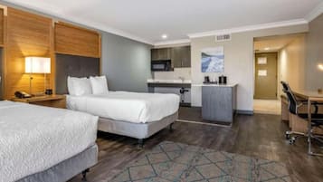 Habitación de hotel con dos camas, escritorio, kitchenette y baño.