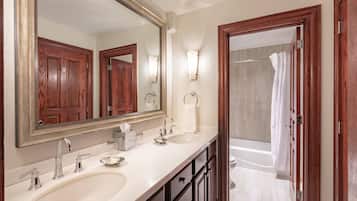 Une salle de bain avec deux lavabos, un grand miroir et un espace douche.