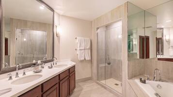 Un baño moderno con lavamanos dobles, un espejo grande, cabina de ducha con mampara de vidrio y muebles de madera.