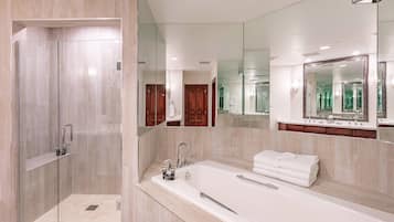 Un baño moderno con ducha envuelta en vidrio, una bañera grande y un lavamanos con espejo.
