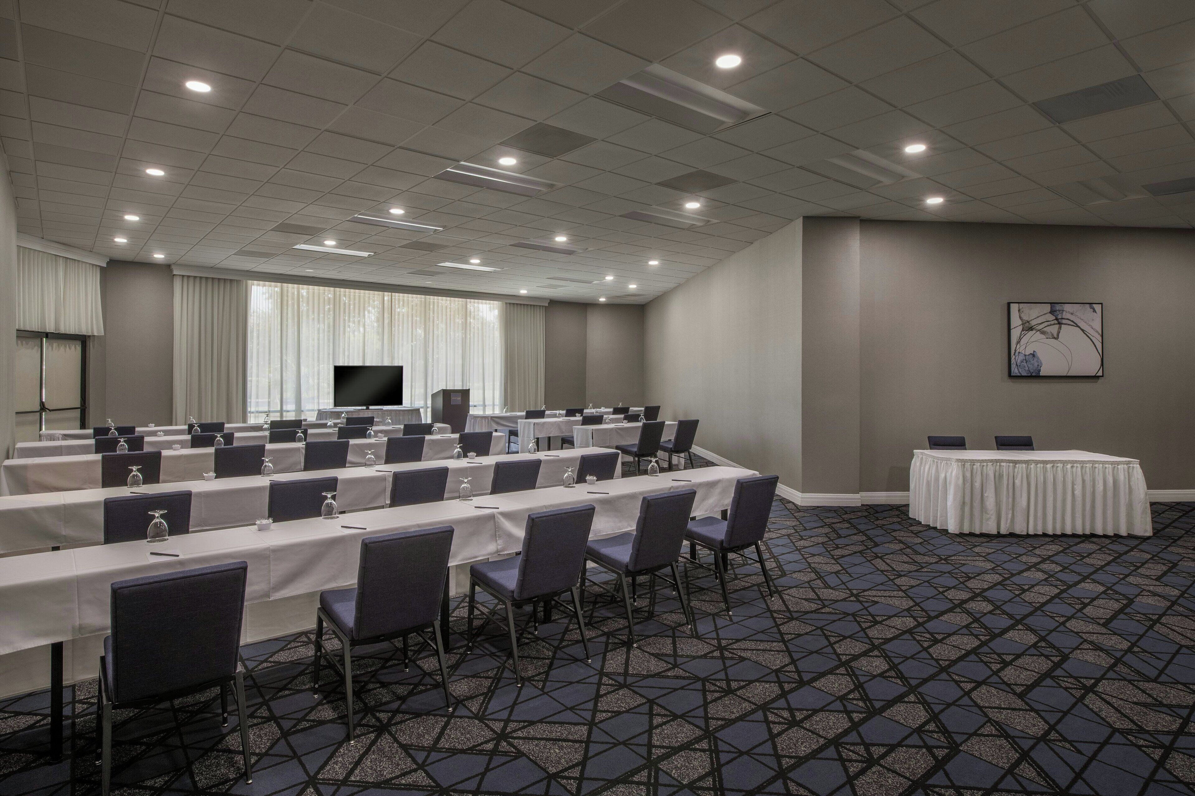 A conference room with a long table, chairs, and a television screen.