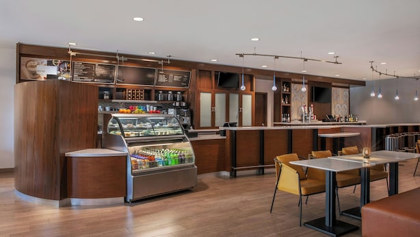 Un café moderne avec un comptoir, un espace salon et un présentoir où sont exposées les boissons.