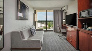 Une chambre d’hôtel avec un canapé, une télévision, un bureau et une vue sur l’extérieur.