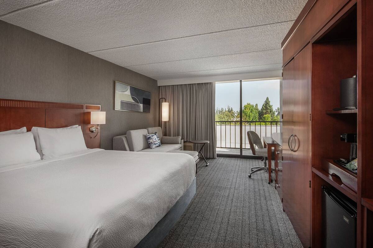 Hotelkamer met een groot bed, een bureau, een stoel, een televisie en een minibar.