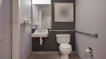 Un baño pequeño con inodoro, lavamanos y barra de apoyo.