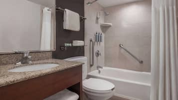 Un baño moderno con lavamanos de granito, inodoro y ducha a ras de suelo con barra de apoyo.