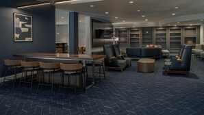 Un hall d’hôtel moderne doté d’un bar, de coins salon et d’une cheminée.