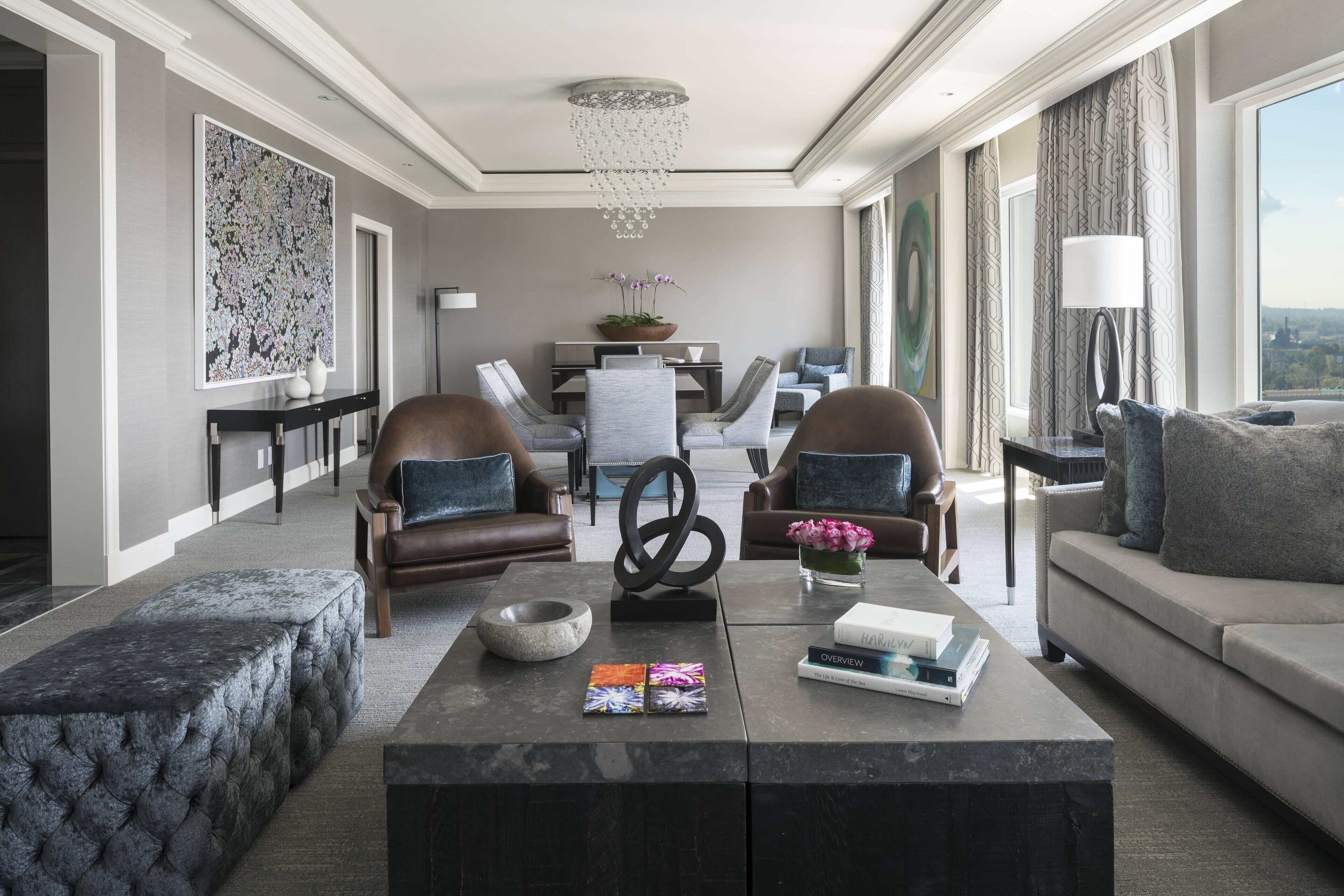 A modern living room with a sofa, two armchairs, a coffee table, and a chandelier.