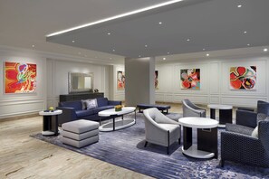 A modern lounge area with a blue and white color scheme, featuring a sofa, armchairs, a coffee table, and a patterned rug.