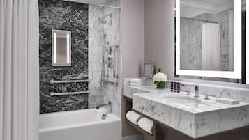 Une salle de bain moderne équipée d’une baignoire, d’une douche et d’un meuble-lavabo avec un grand miroir.