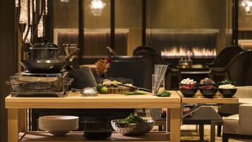 A dining area with a wooden table set with plates, bowls, and a pot on a portable stove.