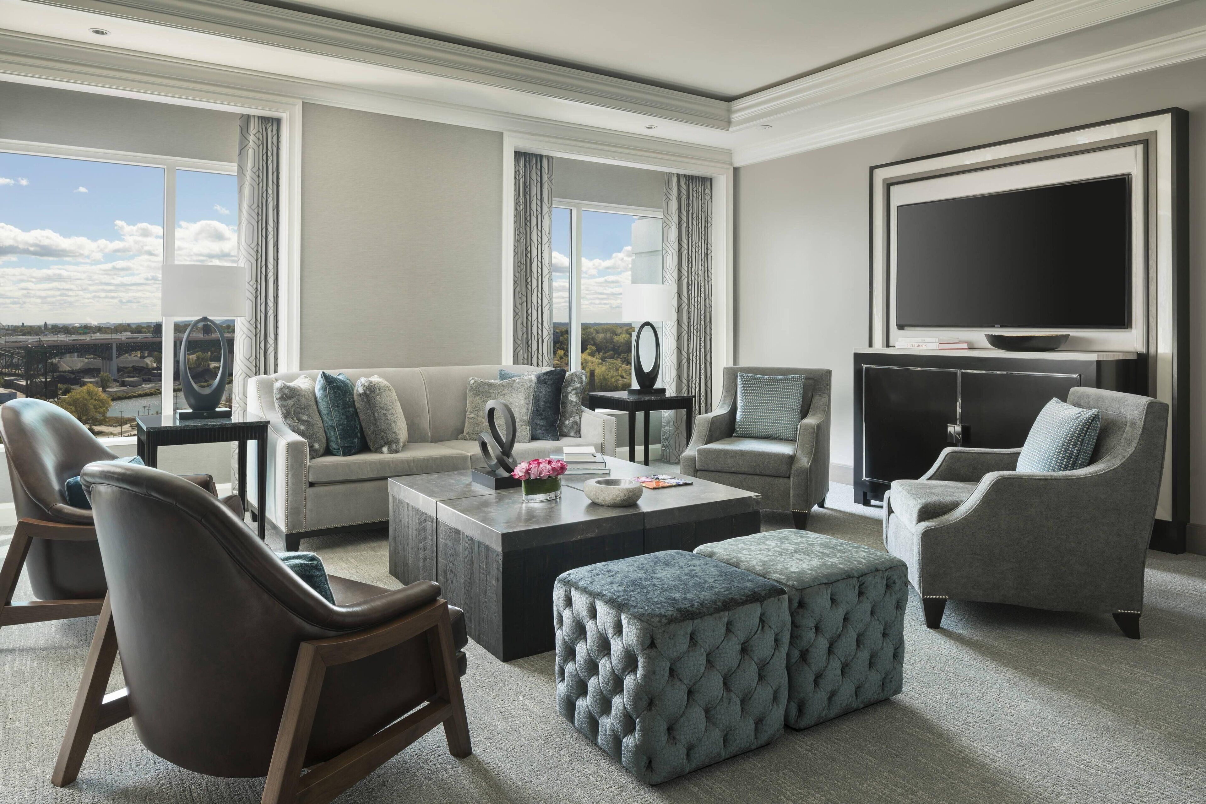 A modern living room with a large flat-screen TV, comfortable seating, and a view of the cityscape.