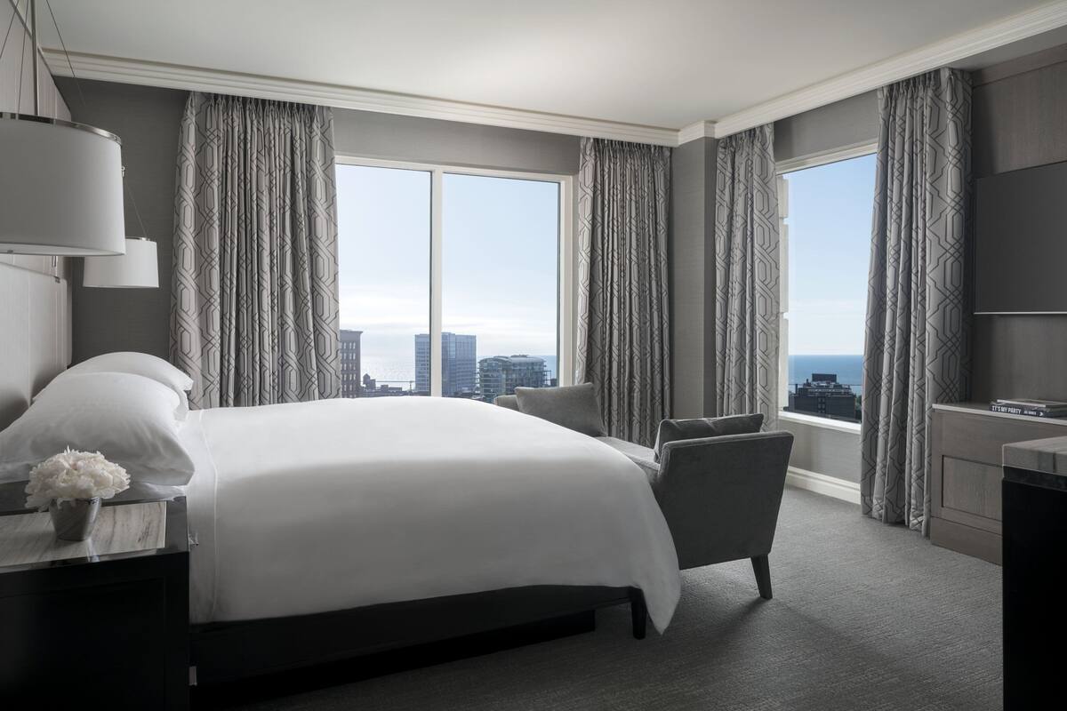 A modern hotel room with a large bed, a view of the cityscape, and a city view through the window.