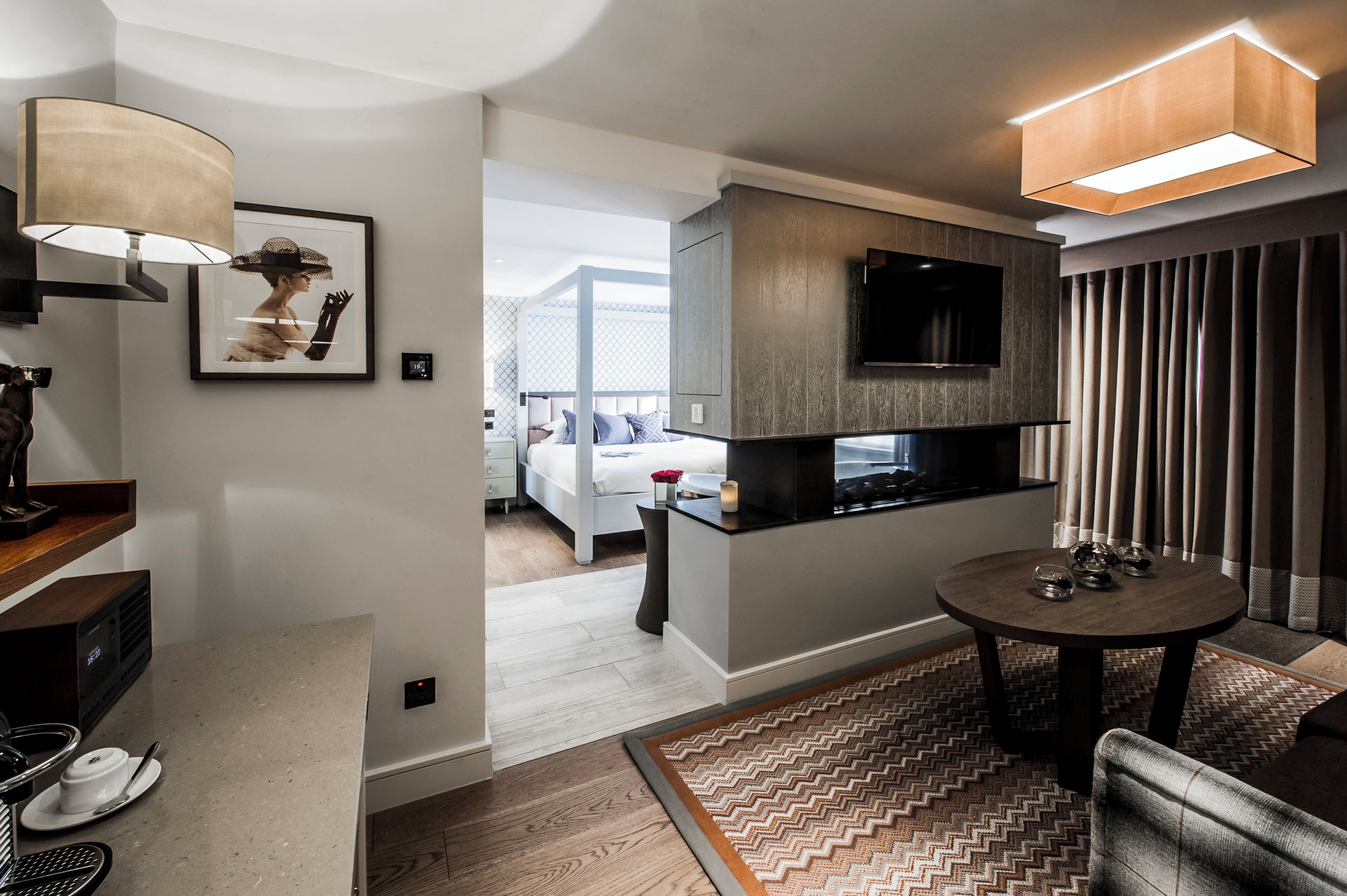 Habitación de hotel moderna con cocina, una mesa de comedor y un televisor montado en la pared.