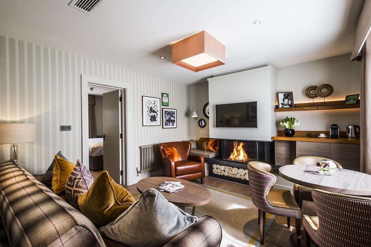 Ein modernes Wohnzimmer mit einer Couch, Sesseln, einem Couchtisch und einem Kamin.
