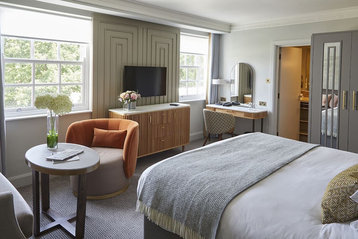 Ein Hotelzimmer mit Bett, Schreibtisch, Sessel, Fernseher und Kleiderschrank.