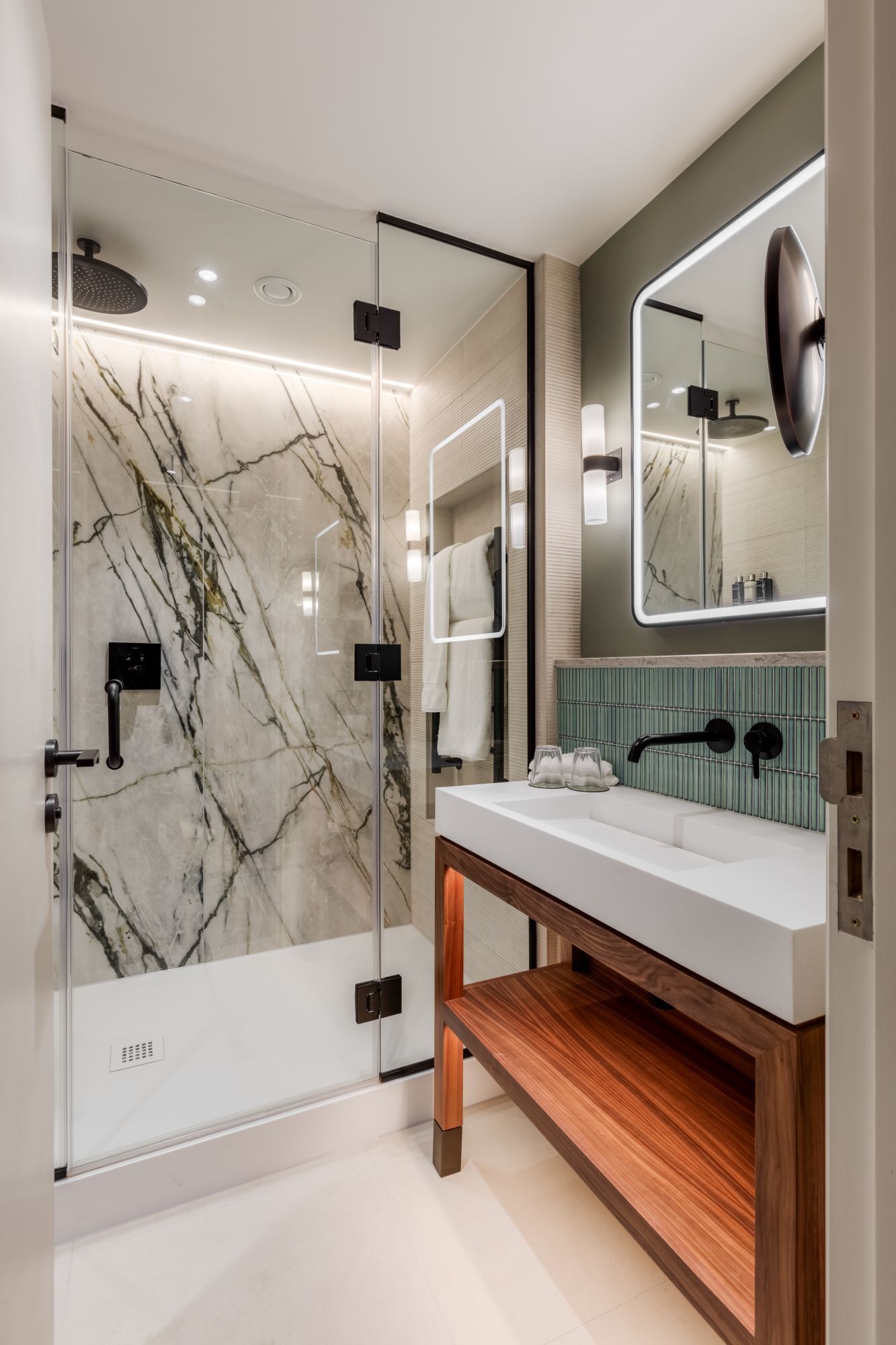 A modern bathroom with a glass-enclosed shower, a wooden vanity, and a large mirror.