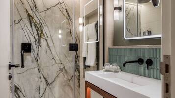 A modern bathroom with a glass-enclosed shower, a wooden vanity, and a large mirror.