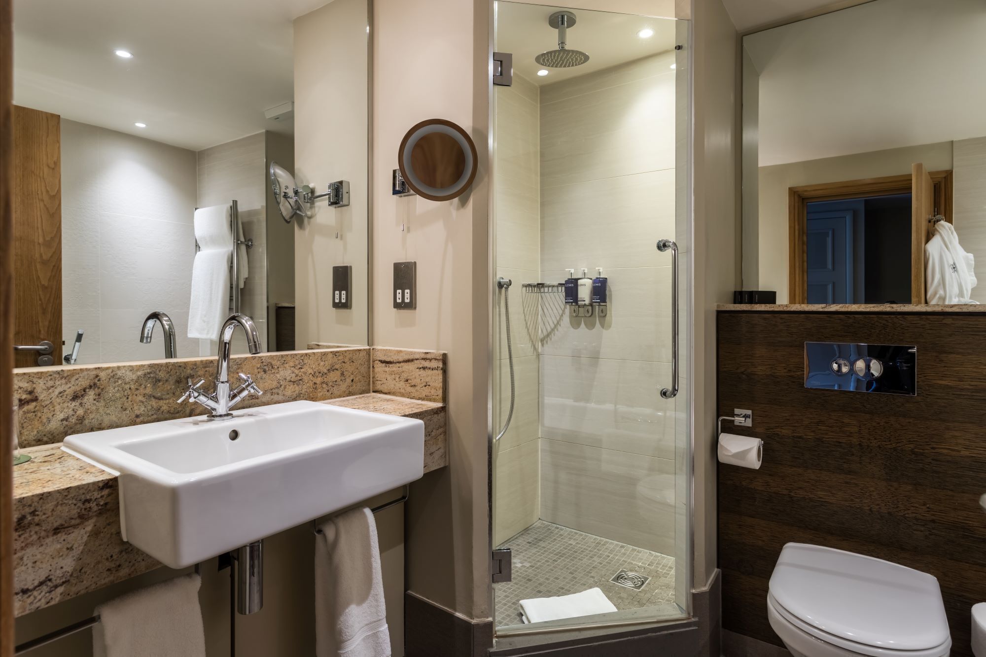 A modern bathroom with a sink, mirror, shower, and toilet.