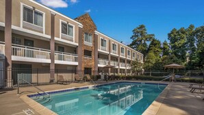 Hotel com piscina, área de estar ao ar livre e fachada de tijolos.