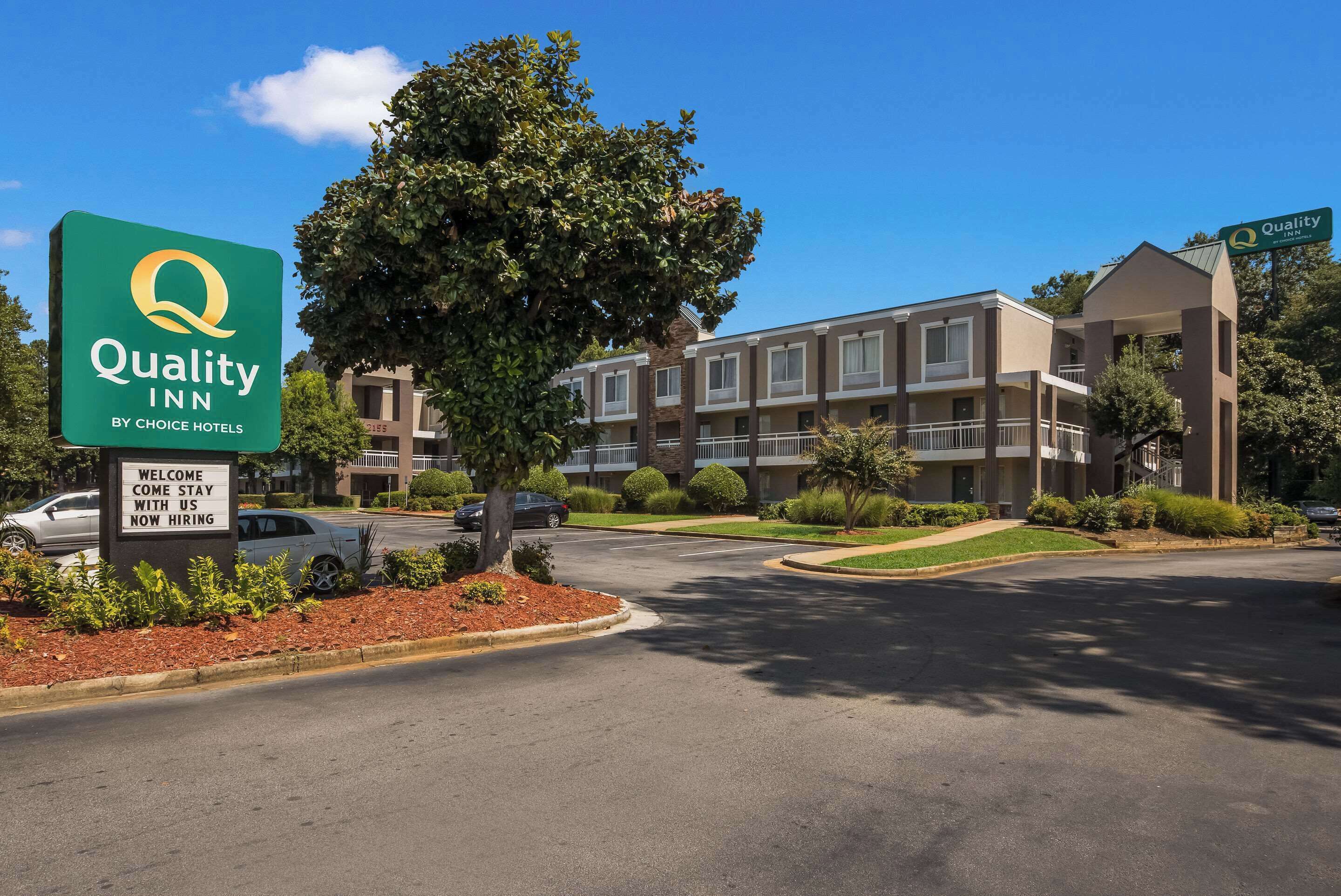 A Quality Inn by Choice Hotels with a welcoming sign, a landscaped entrance, and a multi-story building with balconies.