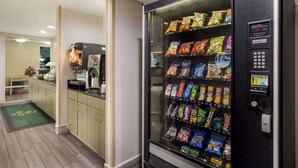Máquina de vendas com lanches e máquina de café numa cozinha de hotel.