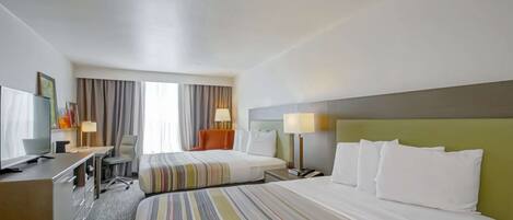 A hotel room with two beds, a desk with a chair, a television, and a window with curtains.