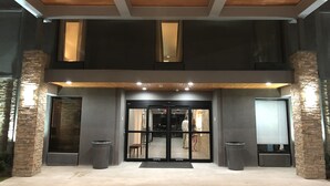 A modern building entrance with a double door, stone pillars, and a wooden ceiling. - Country Inn & Suites by Radisson, New Orleans I-10 East, LA (New Orleans)