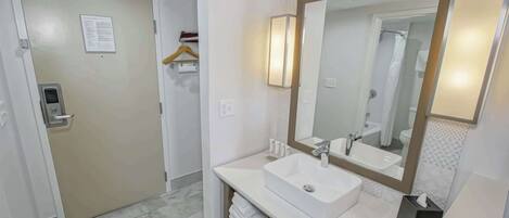 Une salle de bain moderne avec un lavabo blanc, un grand miroir et un porte-serviettes.